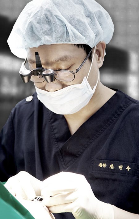 수술모·확대경·마스크 차림으로 수술 중인 김민수 원장
